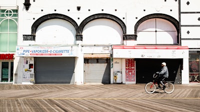 A cyclist rides past shuttered businesses during the coronavirus outbreak on the boardwalk in Atlantic City, N.J., Tuesday, April 28, 2020.
