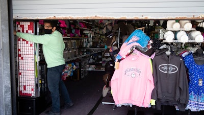 Mohammad Ikram closes a large door to his business Hot Stop, fully stocked but closed during the coronavirus pandemic.