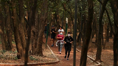 People wearing protective face mask as a precaution against the spread of the new coronavirus jog at Chalputepec park in Mexico City, Sunday, April 26, 2020.