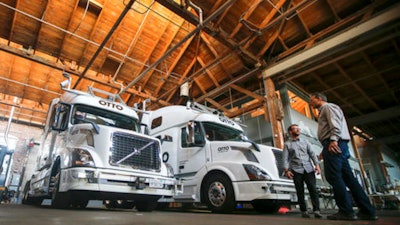 In this Thursday, Aug. 18, 2016, file photo, employees stand next to self-driving, big-rig trucks during a demonstration at the Otto headquarters, in San Francisco. Uber's self-driving startup Otto developed technology allowing big rigs to drive themselves. After taking millions of factory jobs, robots could be coming for a new class of worker: people who drive for a living.