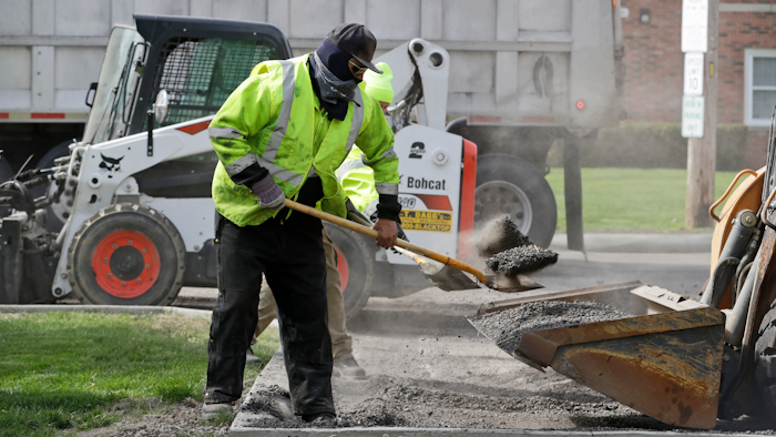 In this May 6 photo, Jarrett Barth, who works for Dagg's Asphalt & Sealcoating, shovels gravel into a backhoe bucket in Lyndhurst, OH.