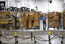 Associates move bins filled with products at the loading dock of Amazon's fulfillment center in Livonia, Mich., March 23, 2018.
