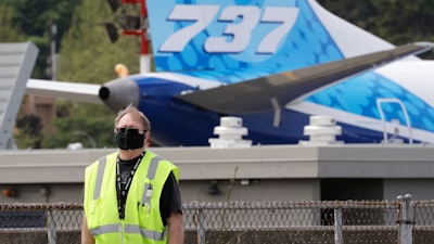 A masked worker walks in view of a 737 jet at a Boeing airplane manufacturing plant.