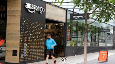 A person wearing a mask jogs past an Amazon Go store.