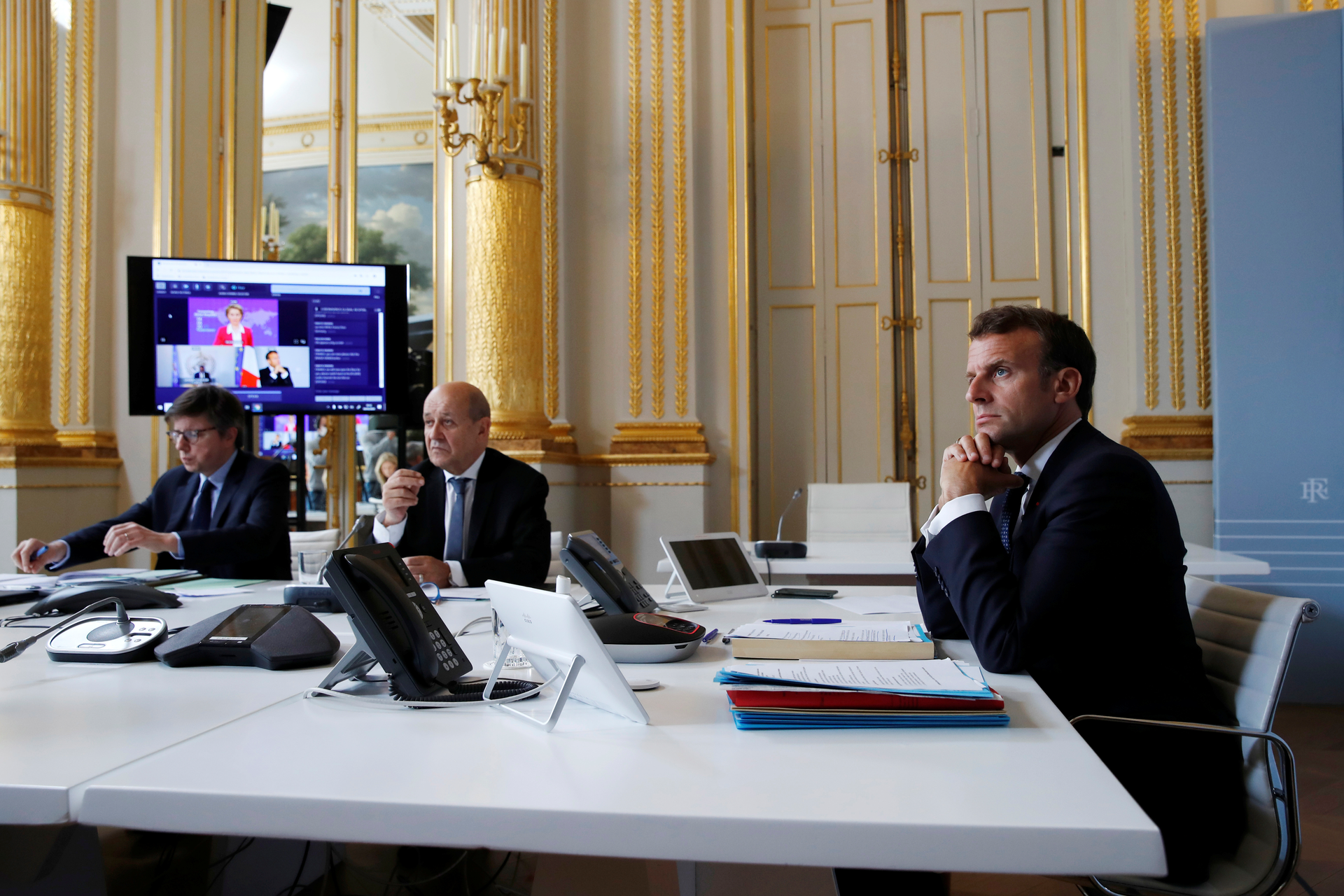 French President Emmanuel Macron, right, and Foreign Minister Jean-Yves le Drian, center, during an international videoconference on vaccination at the Elysee Palace in Paris, May 4, 2020.