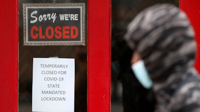 A pedestrian walks by The Framing Gallery, closed due to the COVID-19 pandemic, in Grosse Pointe, MI on Thursday, May 7.