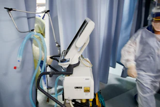 Nurse pulls a ventilator into an exam room.