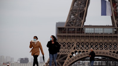 People walk near the Eiffel Tower, in Paris, Monday, May 11, 2020.