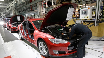 Tesla employees work on Model S cars in the Tesla factory in Fremont, Calif., May 14, 2015.