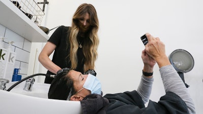 Leslie Musumecci checks a text while Emily Summerville rinses her hair Monday, May 11, 2020.