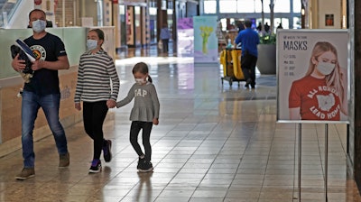 Shoppers walks past a sign encouraging masks at SouthPark Mall, Wednesday, May 13 in Strongsville, OH.