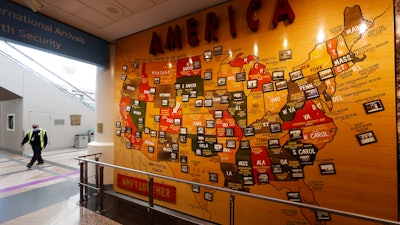 A lone security officer walks past a map of America in the main terminal of Denver International Airport.