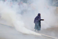 Bangladeshi garment workers run for cover after police fired tear gas to disperse them during a protest in Dhaka, Bangladesh, Wednesday, May 20, 2020.