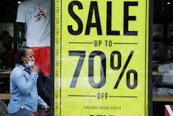 A woman walks past a store advertising sales at 70 percent off.