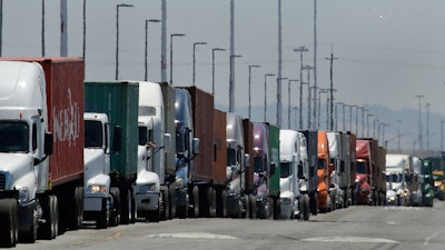 In this July 22, 2019 photo, trucks hauling shipping containers wait to unload at the Port of Oakland in Oakland, CA.