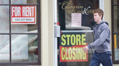 A man walks past a closed business, Wednesday, April 29, 2020, in Chagrin Falls, Ohio. The U.S. economy shrank at a 4.8% annual rate last quarter as the coronavirus pandemic shut down much of the country and began triggering a recession that will end the longest expansion on record.