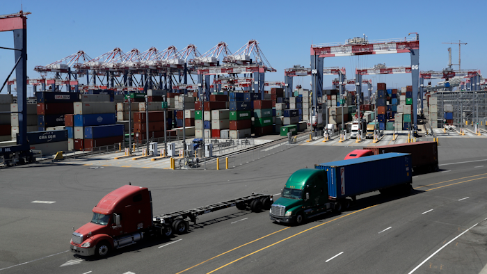 Trucks travel along a loading dock at the Port of Long Beach in Long Beach, Calif.
