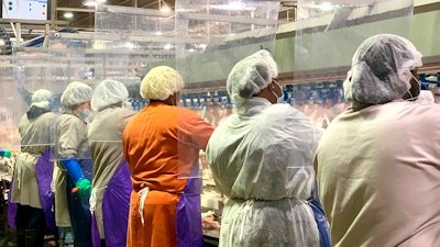 Tyson Foods workers wear protective masks and stand between plastic dividers at the company's Camilla, Georgia poultry processing plant.