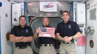 ASA astronauts Robert L. Behnken, left, and Chris Cassidy right, listen as commander Douglas Hurley speaks about retrieving the American flag left behind at the International Space Station nearly a decade ago.