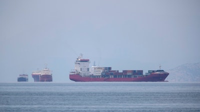 A cargo ship approaches the port of Piraeus as other ships are anchored.