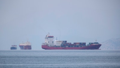 A cargo ship approaches the port of Piraeus as other ships are anchored.