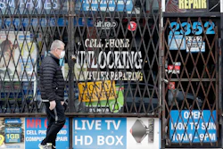 A man walks by a closed store.