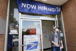 A customer walks out of a U.S. Post Office branch advertising a job opening, Seattle, June 4, 2020.