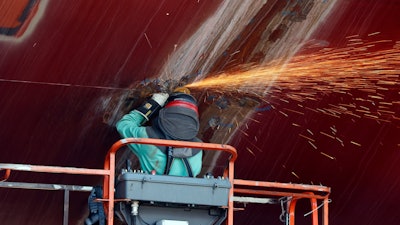 A welder works on the hull of a Zumwalt-class destroyer.