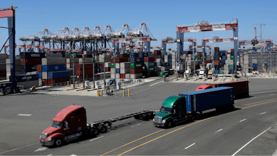 Trucks travel along a loading dock at the Port of Long Beach in Long Beach, Calif.