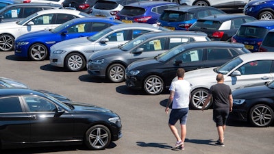 People view cars on the forecourt of a car sales outlet, in Norfolk, England, open for the first time since the lockdown, as part of a wider easing of restrictions in England, Monday June 1, 2020. The British government has lifted some lockdown restrictions to restart social life and activate the economy while still endeavouring to limit the spread of the highly contagious COVID-19 coronavirus.