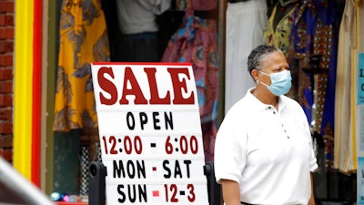 A woman walks past a boutique with a sale sign, Thursday, June 4, 2020, in Cleveland Heights, Ohio. The state says more than 34,000 Ohioans filed unemployment claims during the last week of May. That is the lowest figure since Ohio's stay-at-home orders depressed the economy and led to widespread layoffs.