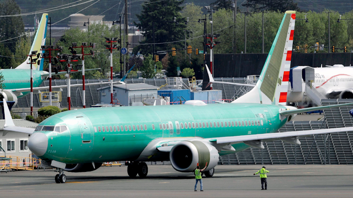 Workers stand near a Boeing 737 Max 8 jetliner being built for American Airlines.