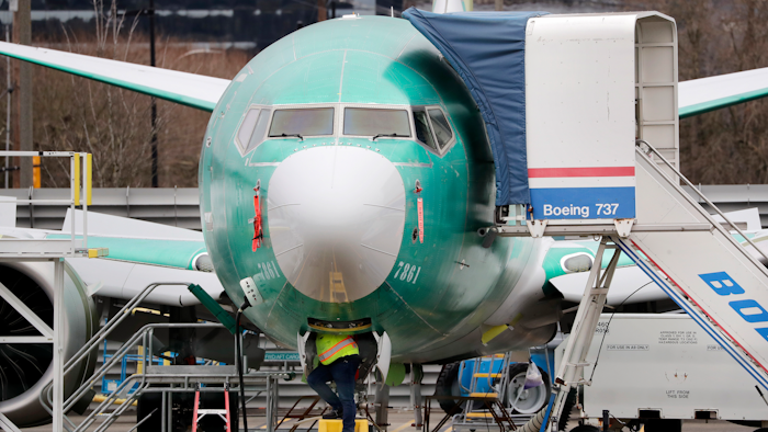 A worker looks up underneath a Boeing 737 Max jet in Renton, Wash., Dec. 16, 2019.