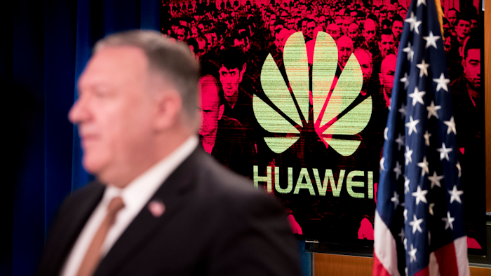 A monitor displays the logo for 'Huawei' behind Secretary of State Mike Pompeo.