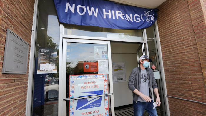 In this June 4 photo, a customer walks out of a US Post Office branch and under a banner advertising a job opening, in Seattle. Unemployment remains painfully high in the US even as economic activity is slowly picking up.
