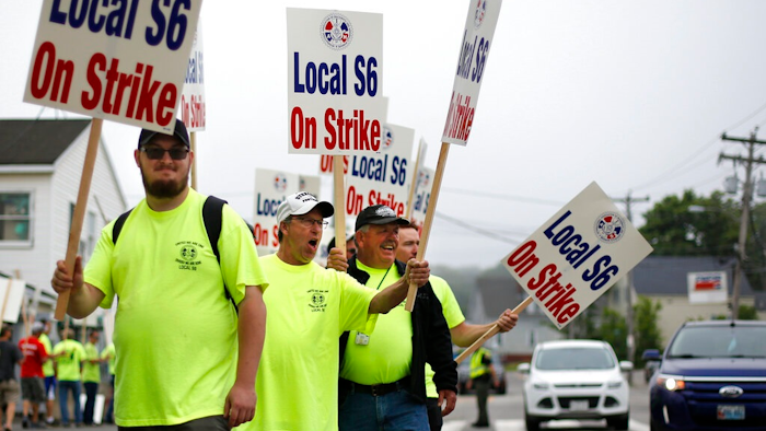 Picketers acknowledge a honking motorist outside an entrance to Bath Iron Works, Monday, June 22, 2020, in Bath, Maine. Production workers at one of the Navy's largest shipbuilders overwhelmingly voted to strike, rejecting the company's three-year contract offer Sunday and threatening to further delay delivery of ships.