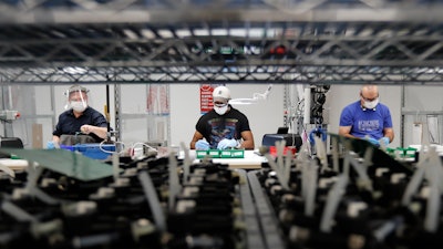 In this May 13, 2020 photo, Ford Motor Co. line workers put together ventilators that the automaker is assembling at the Ford Rawsonville plant in Ypsilanti Township, Mich. American industry rebounded last month as factories began to reopen for the first time since being shut down by the coronavirus in Aprll.