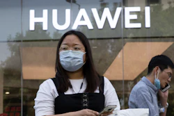 Residents wearing masks to curb the spread of the coronavirus past by a Huawei shop in Beijing.