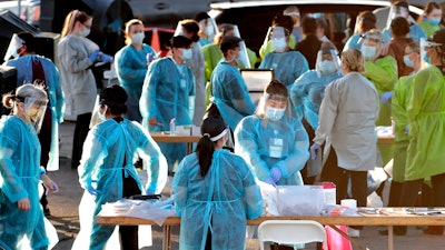 In this June 27 photo, medical personnel prepare to test hundreds of people lined up in vehicles in Phoenix's western neighborhood of Maryvalefor free COVID-19 tests organized by Equality Health Foundation, which focuses on care in underserved communities.