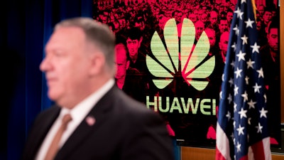 A monitor displays the logo for 'Huawei' behind Secretary of State Mike Pompeo.
