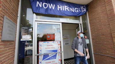 In this June 4 photo, a customer walks out of a US Post Office branch and under a banner advertising a job opening, in Seattle. Unemployment remains painfully high in the US even as economic activity is slowly picking up.