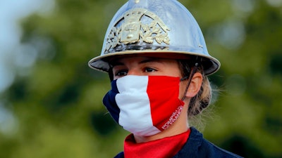 A firefighter wears a face mask with the colors of the French flag.