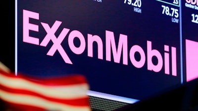 The logo for ExxonMobil appears above a trading post on the floor of the New York Stock Exchange.