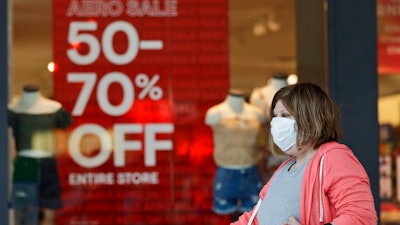 In this June 10, 2020 file photo, a woman walks past a store with sale signs displayed at Great Lakes Mall, in Mentor, Ohio. The Federal Reserve says economic activity has picked up in most regions of the country but still remains well below pre-pandemic levels with the country facing high levels of uncertainty. The Fed reported Wednesday, July 15 that its latest survey of economic conditions around the country found improvements in consumer spending and other areas but said the gains were from very low levels seen when widespread lockdowns push the country into a deep recession.
