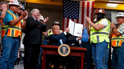 In this April 10, 2019, file photo, President Donald Trump holds up an executive order on energy and infrastructure after signing it at the International Union of Operating Engineers International Training and Education Center in Crosby, Texas. Attorneys general in 20 states and the District of Columbia sued the Trump administration on Tuesday, July 21, 2020, alleging that new federal rules undermine their ability to protect rivers, lakes and streams within their borders. President Trump in April 2019 issued an executive order directing the change that critics said could make it harder for states to block pipelines and other projects over concerns that they could impair water quality.