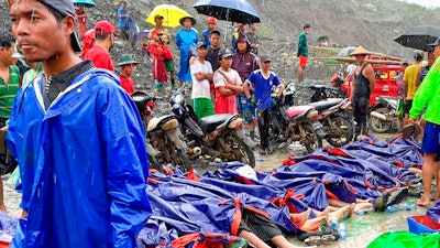 People gather near the bodies of victims of a landslide near a jade mining area in Hpakant, Kachin state, northern Myanmar Thursday, July 2, 2020. Myanmar government says a landslide at a jade mine has killed dozens of people.