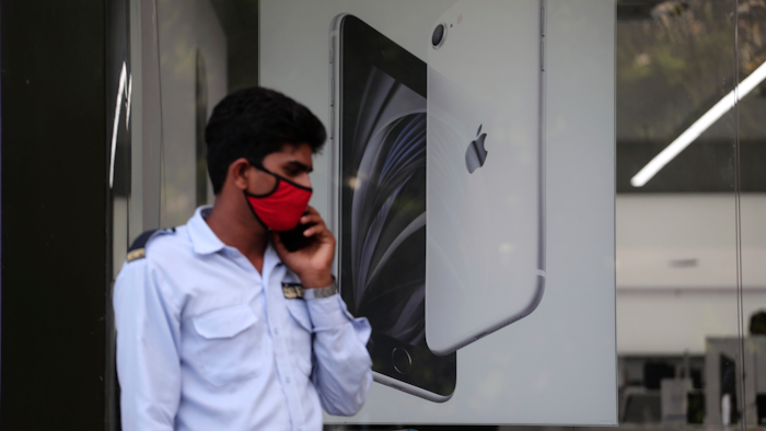 A security officer talks on a phone in front of an image of an iPhone displayed at an Apple store in Ahmedabad, India.