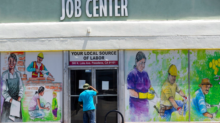 In this May 7, 2020, file photo, a person looks inside the closed doors of the Pasadena Community Job Center in Pasadena, Calif., during the coronavirus outbreak. President Donald Trump’s plan to offer a stripped-down boost in unemployment benefits to millions of Americans amid the coronavirus outbreak has thus far found little traction among the states, which would be required to pick up a quarter of the cost to deliver the maximum benefit.