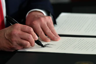 President Donald Trump signs an executive order during a news conference.
