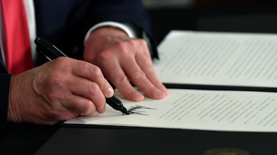 President Donald Trump signs an executive order during a news conference.